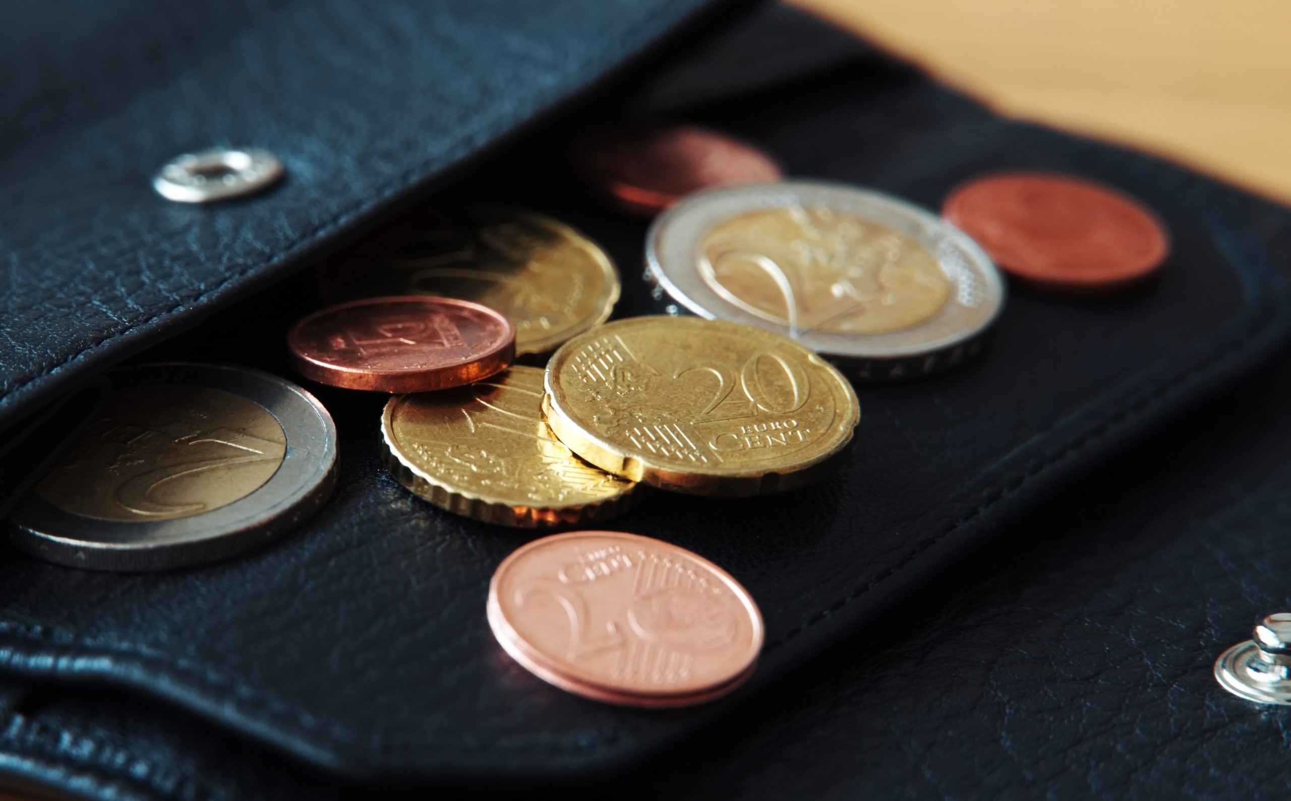 Euro coins in black wallet on wooden table