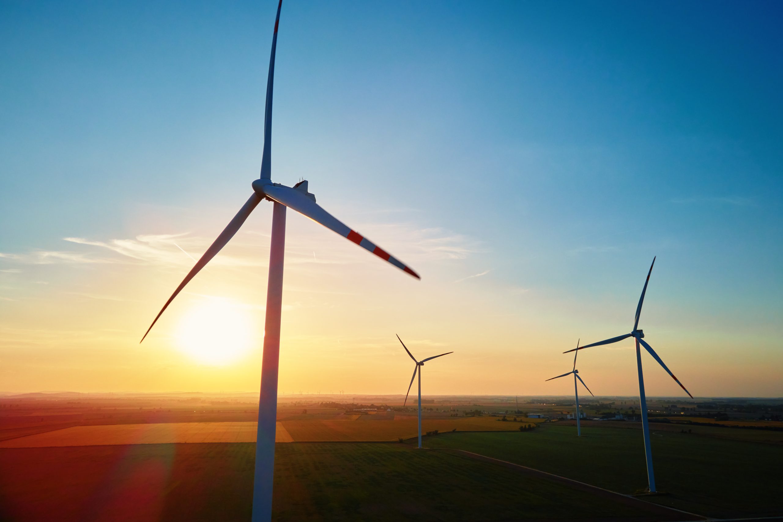 Silhouetted wind turbines in countryside landscape during sunset. Wind power plant generating clean energy. Concept of renewable and sustainable energy